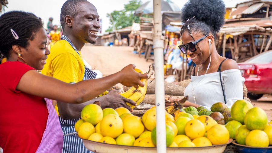 Market vendor serving customers at a fruit stall